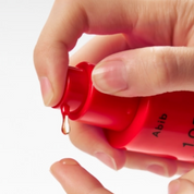Hand holding a red container with 'Abib' branding on a white background