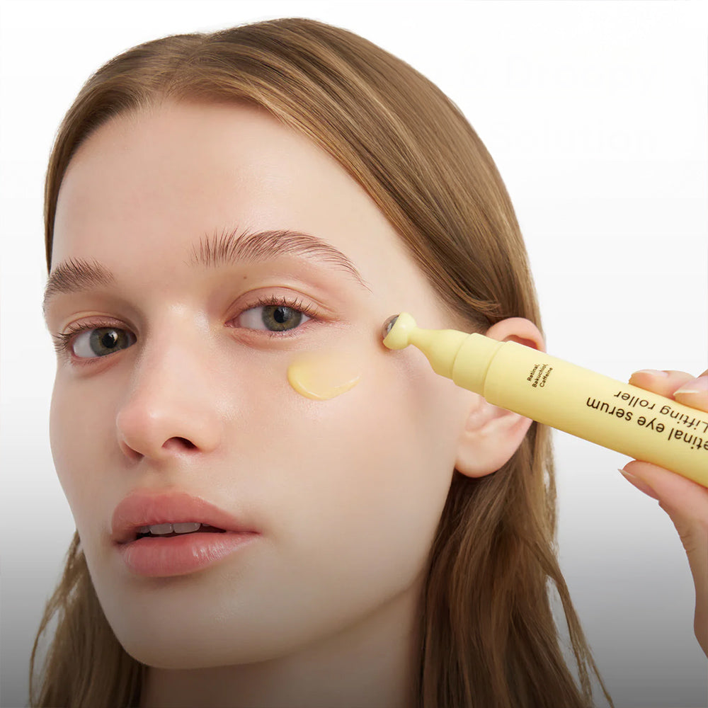 Person applying a yellow cosmetic product to their eye with a applicator.