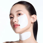 A close-up of a woman with white under-eye and neck patches applied, shown against a clean white background.