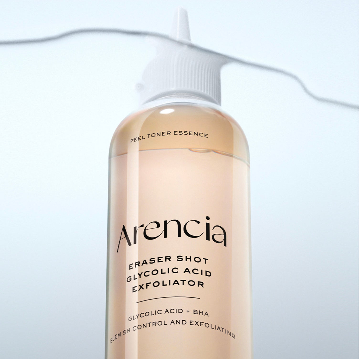 A close-up of an ARENCIA Eraser Shot Glycolic Acid Exfoliator bottle, showing the pale peach-colored liquid and white cap against a light blue-gray gradient background.