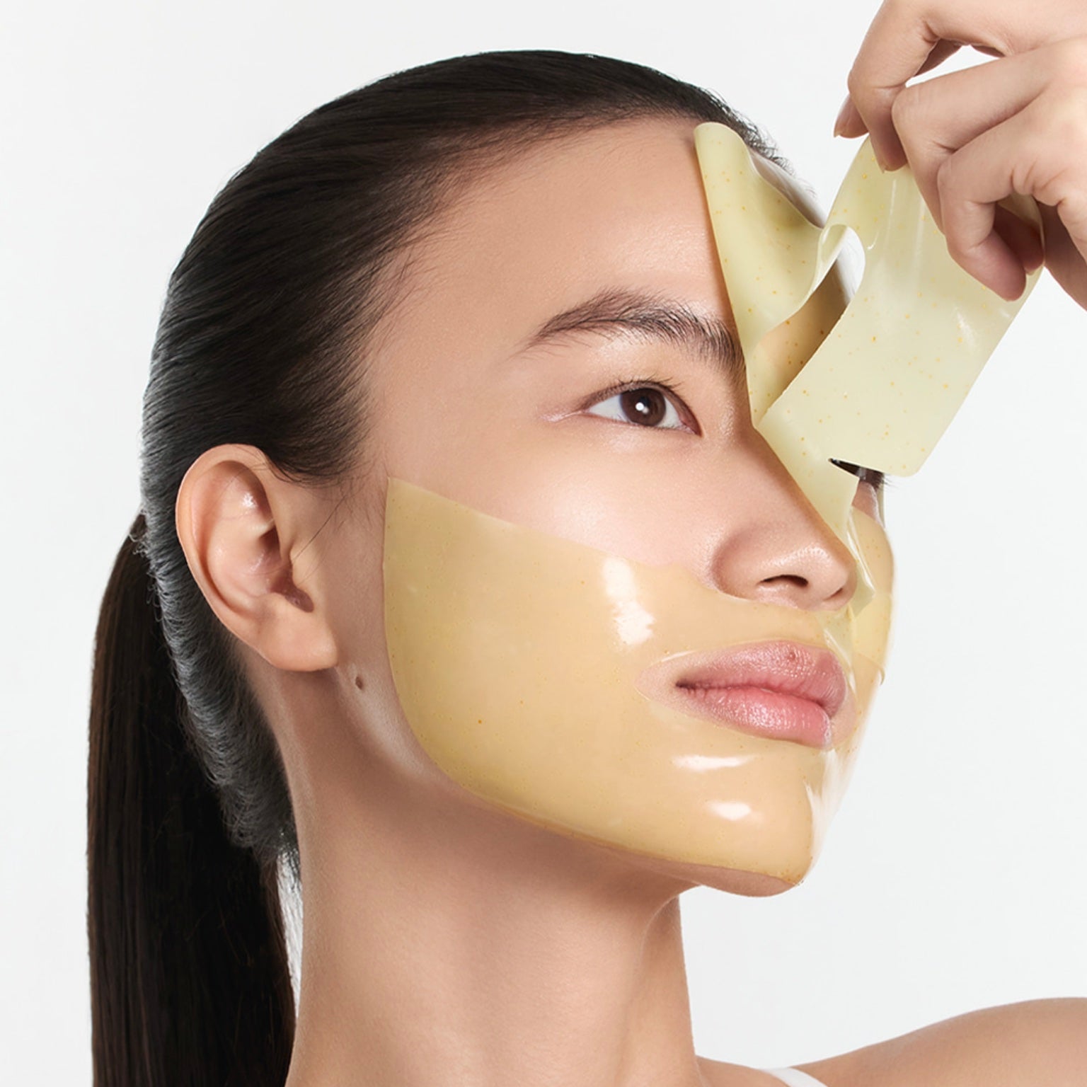 A close-up of a woman applying or ARENCIA Vita Collagen Radiance Jello Mask against a clean white background.