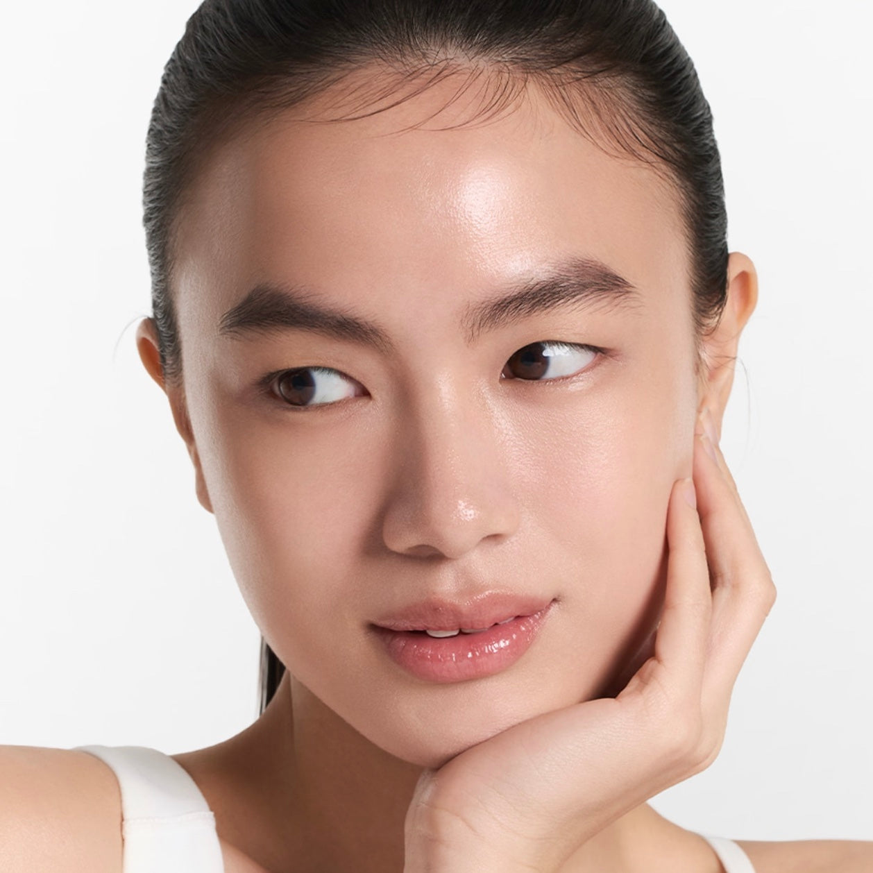 ARENCIA Vitamin C Glow Booster Gel Cream A close-up portrait of a woman with clean, radiant skin and dark hair pulled back, wearing a white strap top against a plain light background.