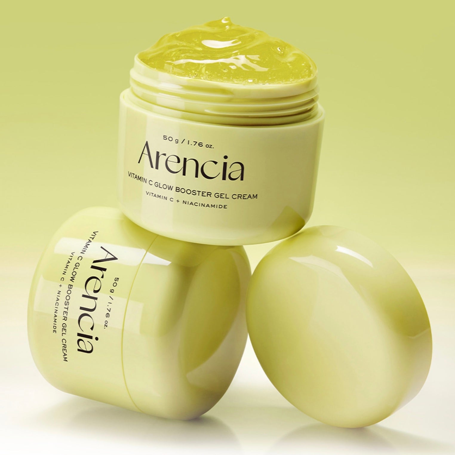 Three jars of Arencia Vitamin C Glow Booster Gel Cream arranged on a light yellow-green background, with one open jar showing the gel cream on top and two closed jars beside it.