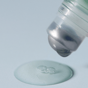 Close-up of a AROMATICA Rosemary Root Volumizing Scalp Ampoule cap being placed on a flat surface with a light gray background