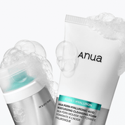 Anua skincare product with cleansing foam and sheet mask on a white background