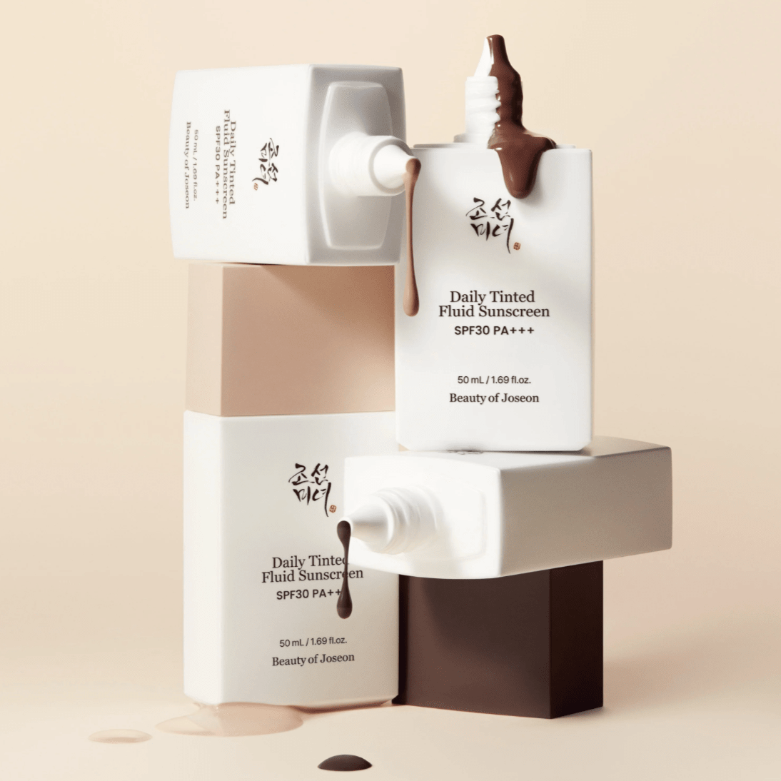 Two bottles of 'Daily Tinted Fluid Sunscreen' by Beauty of Joseon on a beige background.