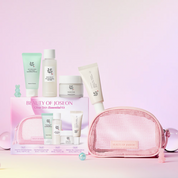 Beauty of Joseon Glow Skin Essential Kit (4-Piece Gift Set) displayed with its pink mesh pouch, skincare bottles, tubes, and box on a pastel pink background.