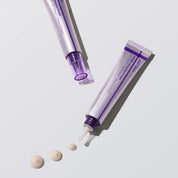 Two tubes of eye cream with a droplet on a light gray background