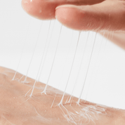 Close-up of COSRX Advanced Snail Peptide Eye Cream a hand applying clear adhesive strip to skin with white cream.