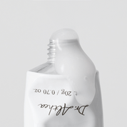 A close-up of a white squeeze tube with a clear cap, showing a glossy white product dripping from the top. The tube has black text reading Dr althea.