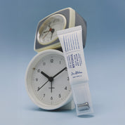 DR. ALTHEA Retinol Flat Iron Eye Roller standing in front of clocks with light blue background
