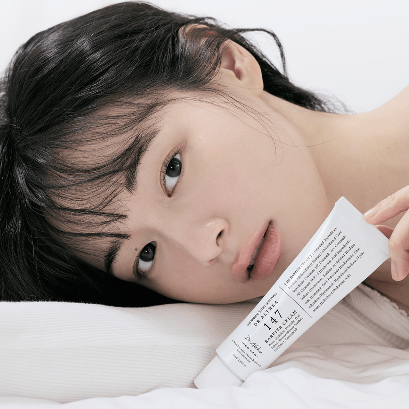 Person holding a Dr althea 147 Barrier cream packaging with a white background