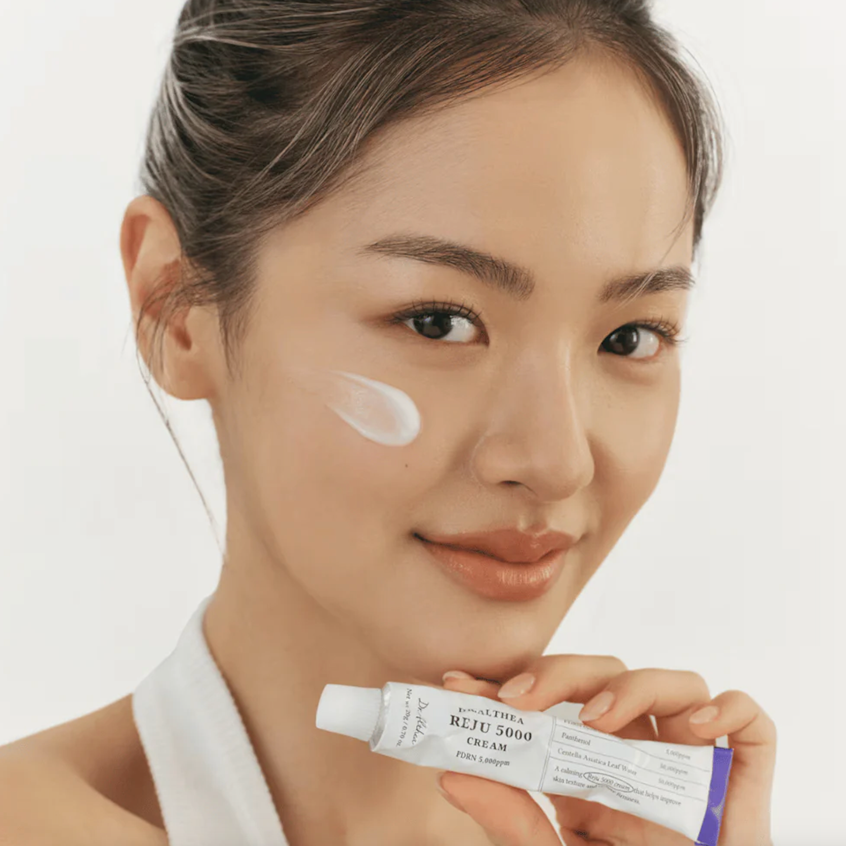 Women holding Dr.Althea PDRN Reju 5000 Cream tube and white cream texture on the face