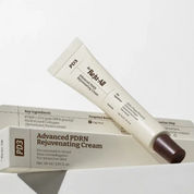 A white cosmetic cream tube labeled Dr. Reju-All Advanced PDRN Rejuvenating Cream resting diagonally across its matching white product box, with a dark brown cap visible on the tube.