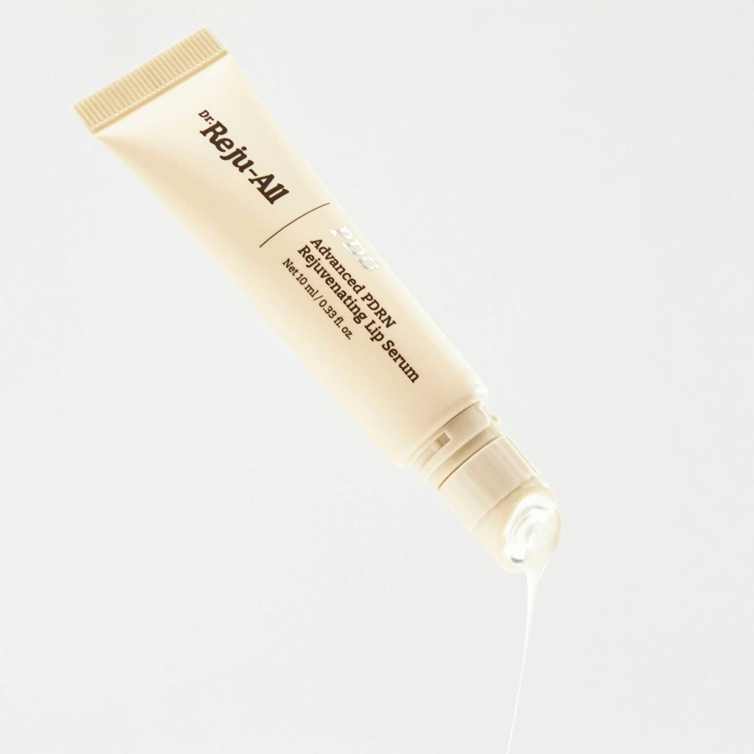 A tube of Dr. Reju-All Advanced PDRN Rejuvenating Lip Serum (10ml), shown tilted on a clean white background with a single drop of white serum dripping from the cap.