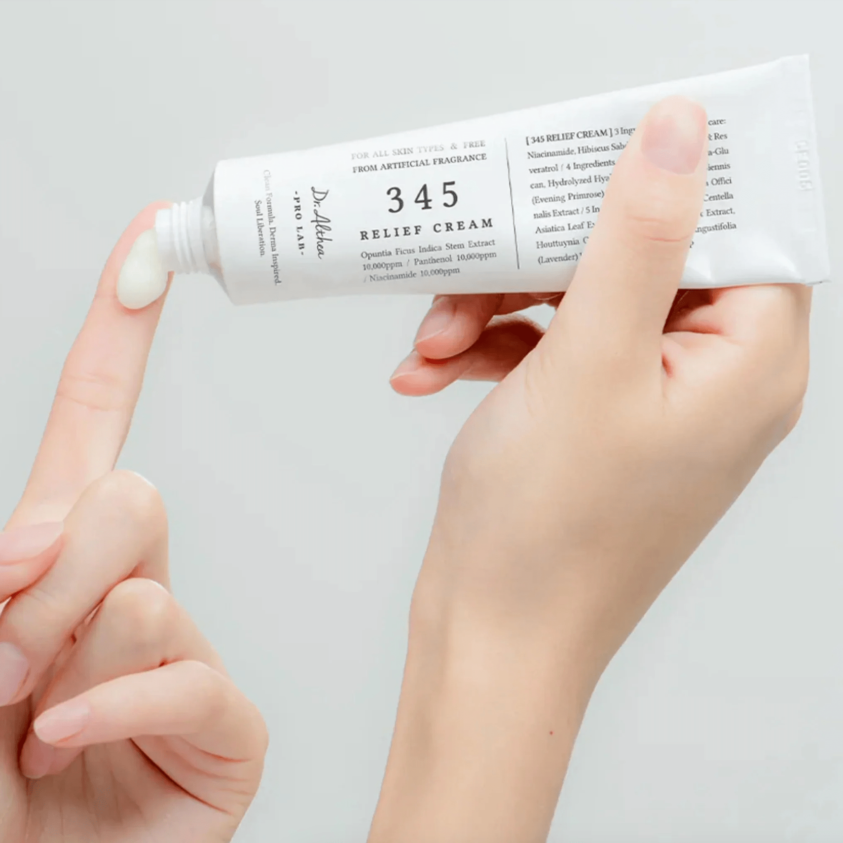 Hand holding a tube of DR ALTHEA 345 Relief Cream against a light gray background