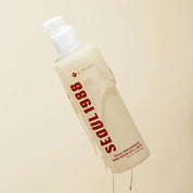 A bottle of K-SECRET SEOUL 1988 Essence Snail Mucin 97% + Rice, featuring a frosted off-white body with red text and a white pump dispenser, set against a solid beige background.
