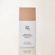 Daily Tinted Fluid Sunscreen bottle with beige cap on a light beige background