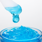 A close-up of MEDICUBE Hyaluronic Ceramide Jelly Cream bright blue translucent gel or slime being lifted from a clear glass container with a frosted spatula, against a clean white background.