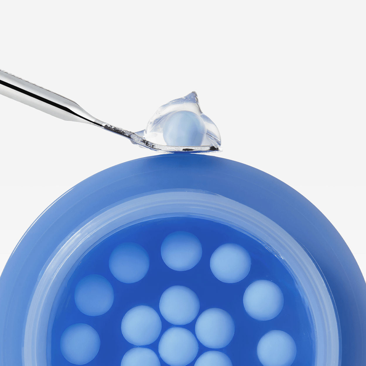 Blue capsule with a spoonful of blue substance on a white background