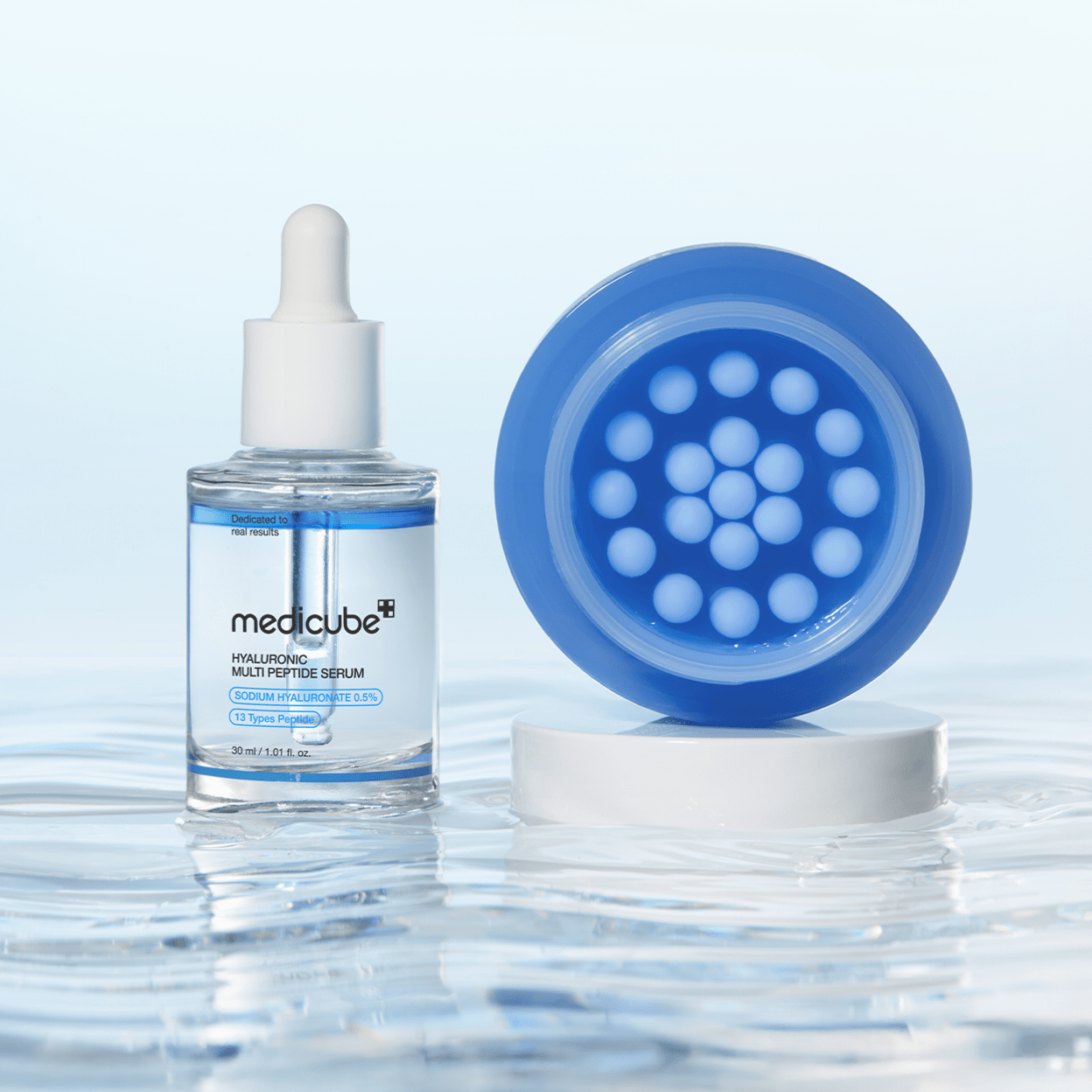 Medicube skincare serum bottle with blue disc on a reflective water surface