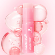 A pink cosmetic balm tube labeled medicube 5% Collagen Volume Multi-Balm, centered among translucent pink bubbles on a soft pink background.