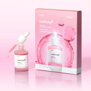 Medicube Fresh Pink Peptide Serum Mask set, featuring a pink serum bottle with a white dropper next to its pink packaging box on a light pink reflective background.
