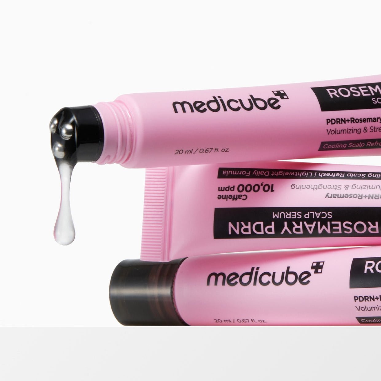 Pink tubes of Medicube hair care product with a droplet of serum on a white background
