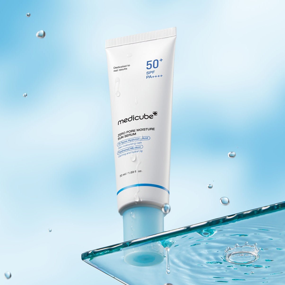 Medicube sunscreen tube with water droplets on a blue background