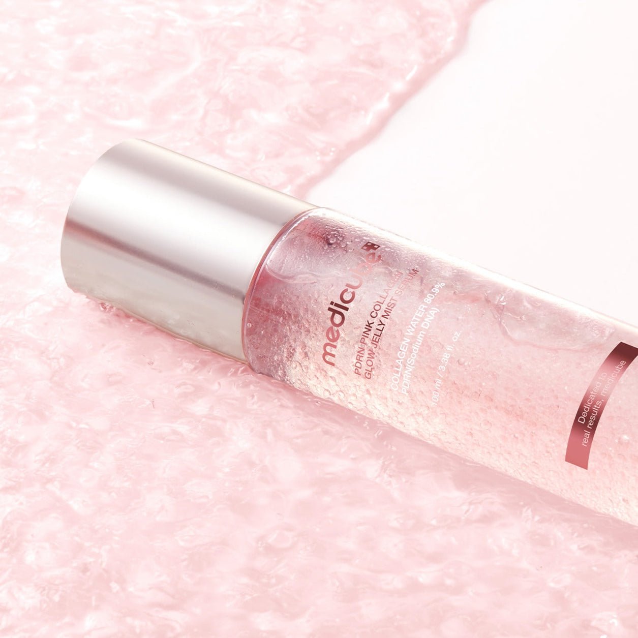 MEDICUBE PDRN Pink Collagen Glow Jelly Mist Serum on a pink textured background