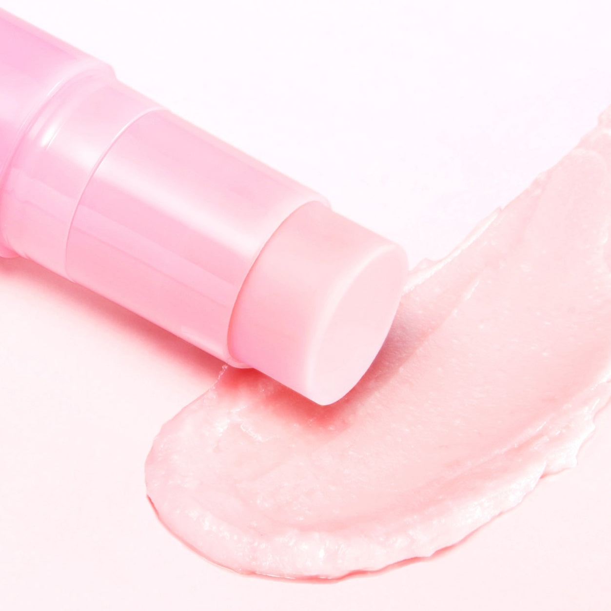 A close-up of a MEDICUBE PDRN Pink Collagen Volume Multi Balm applicator resting on a thick, swirled smear of pale pink cream or gel on a light pink background.