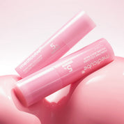 Two pink MEDICUBE PDRN Pink Collagen Volume Multi Balm sticks resting on a glossy pink surface against a soft pink background.