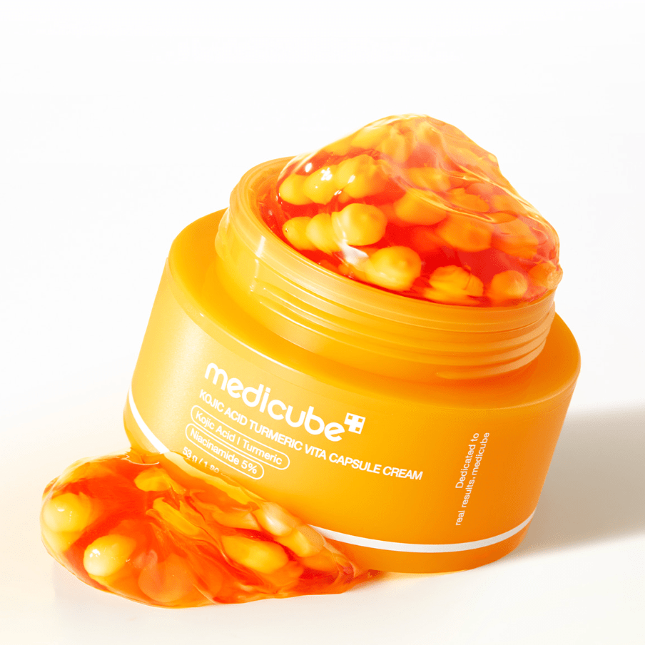 Orange jar of Medicube KOJIC ACID TURMERIC VITA CAPSULE CREAM with visible capsules on a white background