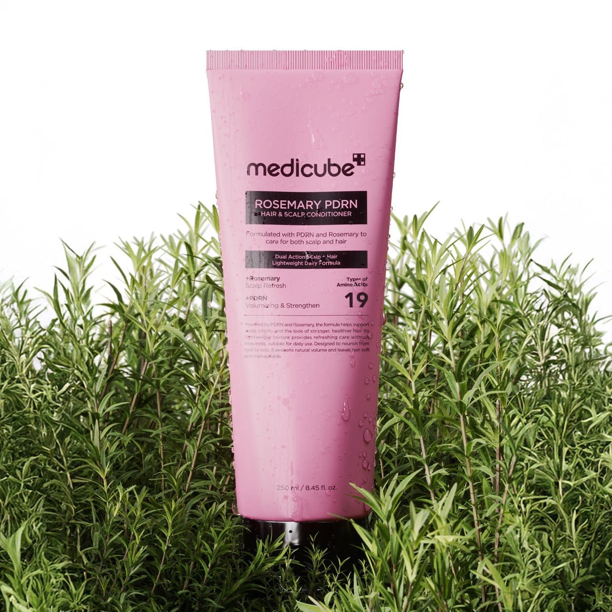 Pink tube of Medicube Rosemary Pdn conditioner surrounded by green plants