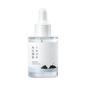 Skincare dropper bottle with a ROUND LAB 1025 Dokdo Ampoule on a white background