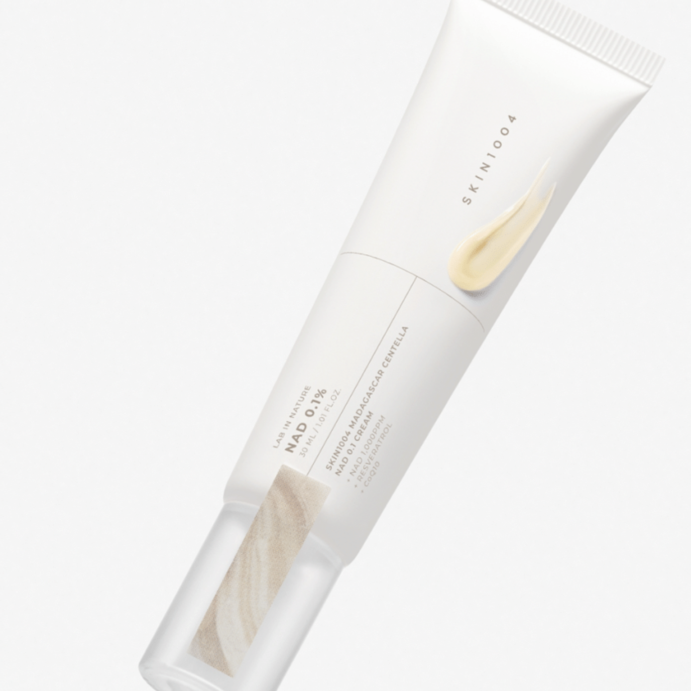 A white squeeze tube of SKIN1004 Madagascar Centella NAD 0.1 Cream, featuring a light beige cream smear graphic on the front, set against a clean white background.