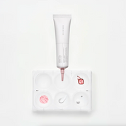 SKIN1004 Madagascar Centella PDRN 1.5 Cream tube with pink detailing is positioned above a white palette tray containing pink cream and a white cream swatch, on a clean white background.