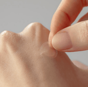 Close-up of a hand holding a small SOME BY MI Clear Spot Patch a neutral background