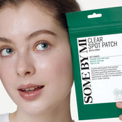 Person holding a package of 'Some By Mi' clear spot patches next to their face.