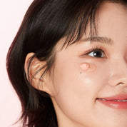 Close-up of a person with a small droplet on their cheek against a pink background