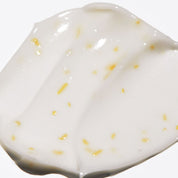 Close-up of VT COSMETICS PDRN Reedle Shot Eye Lifter  a white creamy substance with yellow specks on a white background
