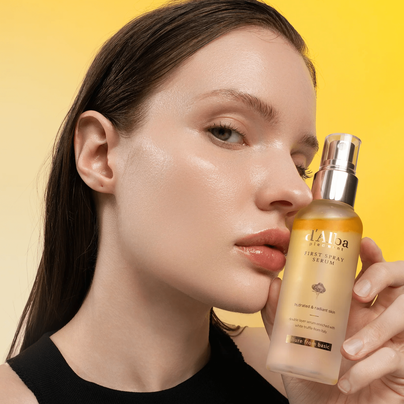 Woman holding d'Alba White Truffle First Spray Serum with a yellow background