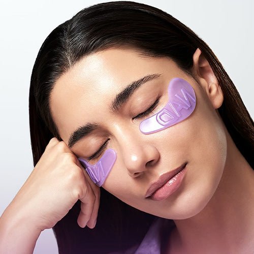 Woman wearing numbuzin purple eye masks on a plain background